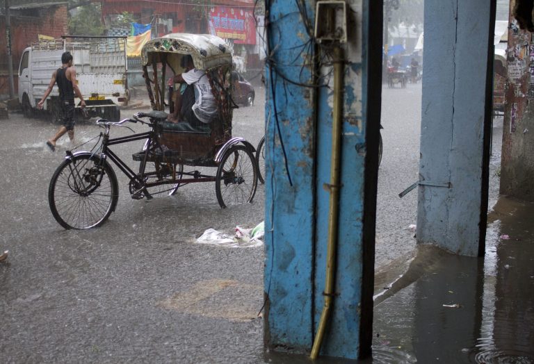 FILE - In this Sept. 29, 2013 file photo, an Indian rickshaw puller sits a top the passenger seat to protect himself  during heavy downpour in Allahabad, India. Scientists looking at 16 cases of wild weather around the world last year see the fingerprints of man-made global warming on more than half of them. Researchers found that climate change increased the odds of nine extremes: Heat waves in Australia, Europe, China, Japan and Korea, intense rain in parts of the United States and India, and severe droughts in California and New Zealand. (AP Photo/ Rajesh Kumar Singh, File)