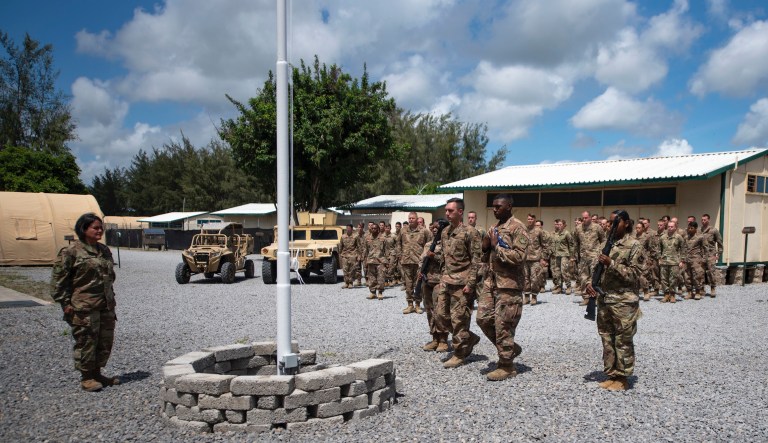 In this photo taken Aug. 26, 2019 and released by the U.S. Air Force, airmen from the 475th Expeditionary Air Base Squadron conduct a flag-raising ceremony, signifying the change from tactical to enduring operations, at Camp Simba, Manda Bay, Kenya.