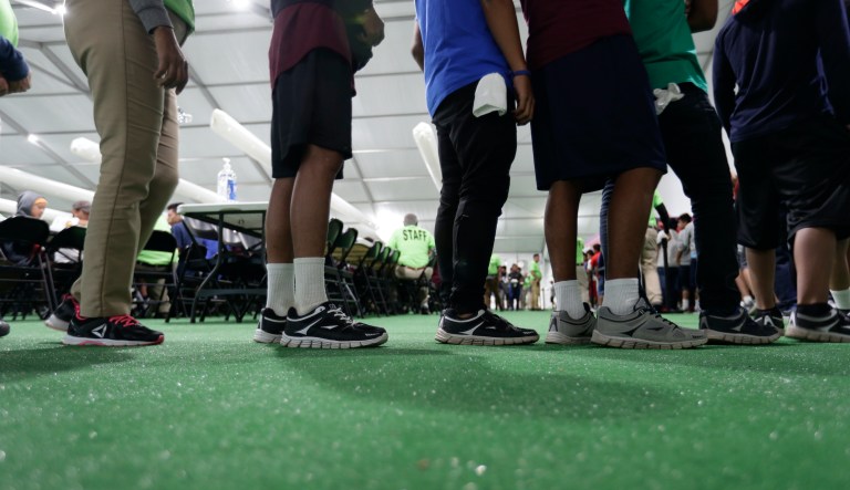 In this July 9, 2019 photo, immigrants line up in the dinning hall at the U.S. government's newest holding center for migrant children in Carrizo Springs, Texas. 