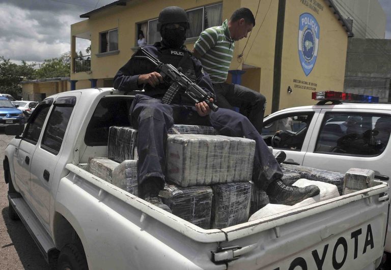   FILE - In this Tuesday July 3, 2012 file photo, a Honduras national policeman sits on packages of cocaine that were brought to Tegucigalpa, Honduras. The cocaine was seized from a small airplane that crashed after it was being chased by military planes and helicopters of the Honduras army near the town of Los Lirios, about 217 miles (350 km) east of Tegucigalpa. Three-quarters of all U.S.-bound cocaine passes through Honduras, an illicit business that has led to an explosion of violence. Honduras has more murders than any other country in the world, says the World Health Organization.(AP Photo/Fernando Antonio, file)  