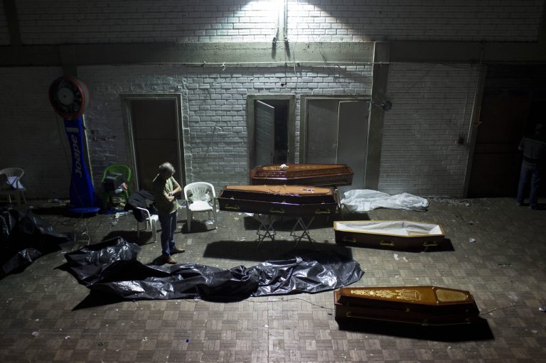 CORRECTS ANNIVERSARY DATE OF FIRE - FILE - In this Jan. 27, 2013 file photo, a man stands near coffins containing the remains of victims from a nightclub fire after the bodies were identified at a gymnasium in Santa Maria city, Rio Grande do Sul state, Brazil. Never again, officials vowed a year ago, would Brazil see a horror like the nightclub fire that killed 242 young men and women, all suffocated by toxic smoke that filled a windowless bunker of a building with no emergency exits. Yet as Brazil marks the anniversary Monday, Jan. 27, 2014, of the deadly blaze at the Kiss nightclub, almost nothing concrete has been done at any level of government to improve fire safety. (AP Photo/Felipe Dana, File)