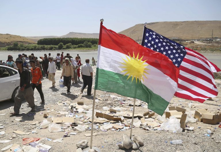 U.S. and Kurdish flags flutter in the wind while displaced Iraqis from the Yazidi community cross the Syria-Iraq border at Feeshkhabour bridge over the Tigris River at Feeshkhabour border point, in northern Iraq, Sunday, Aug. 10, 2014. Kurdish authorities at the border believe some 45,000 Yazidis passed the river crossing in the past week and  thousands more are still stranded in the mountains. (AP Photo/ Khalid Mohammed)