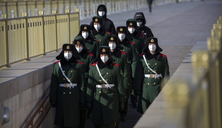 Paramilitary policemen wear face masks as they march in formation into a pedestrian underpass next to Tiananmen Square in Beijing, Tuesday, Feb. 4, 2020. China said Tuesday the number of infections from a new virus surpassed 20,000 as medical workers and patients arrived at a new hospital and President Xi Jinping said "we have launched a people's war of prevention of the epidemic."