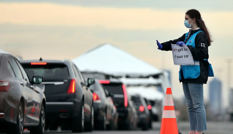 Philadelphia Medical Reserve Corps volunteer Emma Ewing, a sophomore at Temple University, directs cars at the city's coronavirus testing site next to Citizens Bank Park in South Philadelphia on Friday, March 20, 2020. The site, which opened Friday afternoon, is the first city-run drive-through location where people can be swabbed to determine if they have the coronavirus. At the time of opening, it was only for people with symptoms who are over 50 and healthcare workers with symptoms.