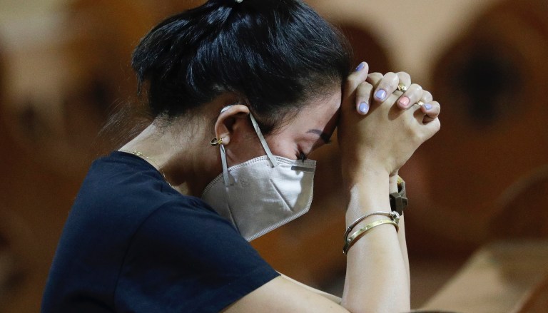 A woman wearing a protective mask prays during a Mass at Manila's Chinatown, Philippines on Thursday, Jan. 30, 2020. 