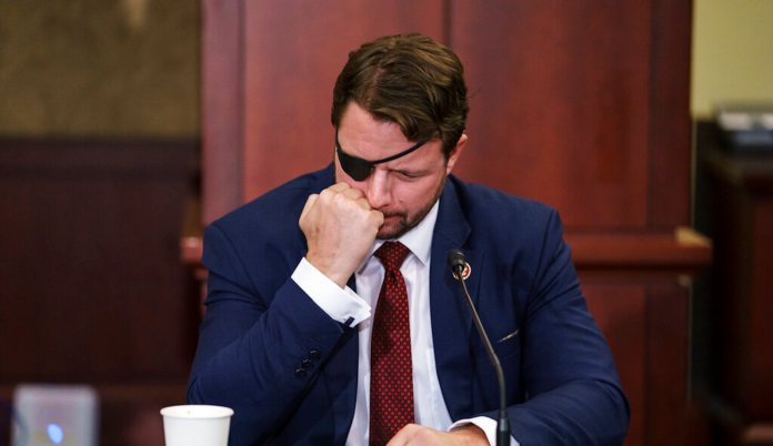 Rep. Dan Crenshaw, R-Texas, left, comes on stage to hand President Donald Trump what he says is the "No" vote card from Wednesday's House impeachment vote as Trump speaks at the Turning Point USA Student Action Summit at the Palm Beach County Convention Center in West Palm Beach, Fla., Saturday, Dec. 21, 2019.