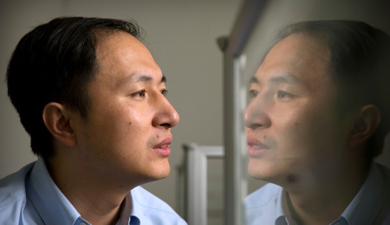 In this Oct. 10, 2018, file photo, He Jiankui is reflected in a glass panel as he works at a computer at a laboratory in Shenzhen in southern China's Guangdong province. A Chinese investigation says Chinese scientist He, behind the reported birth of two babies whose genes had been edited in hopes of making them resistant to the AIDS virus, acted on his own and will be punished for any violations of the law. 