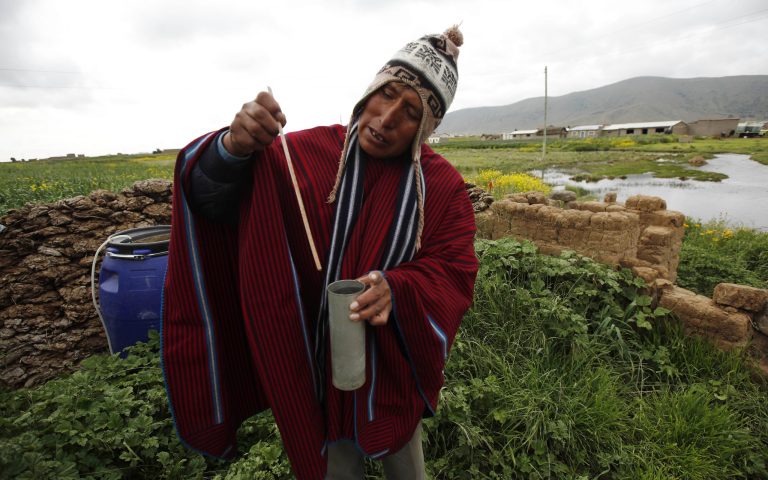 In this Feb. 14, 2014 photo, farmer and traditional meteorologist Francisco Condori measures rain water with a flow meter in Cutusuma, on Lake Titicaca's southern shore in Bolivia. Condori is a well-heeded font of ancestral knowledge for fellow farmers in these treeless climes frequently punished by frosts, hailstorms and drought. (AP Photo/Juan Karita)