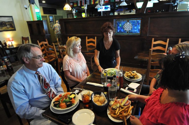 In this July 18, 2014 photo, Dawn Heigl, a waitress at The Harp, serves food at the restaurant in Wilmington, N.C. The Commerce Department reports how much U.S. consumers spent and earned in June on Friday, Aug. 1, 2014. (AP Photo/The Star-News, Matt Born)