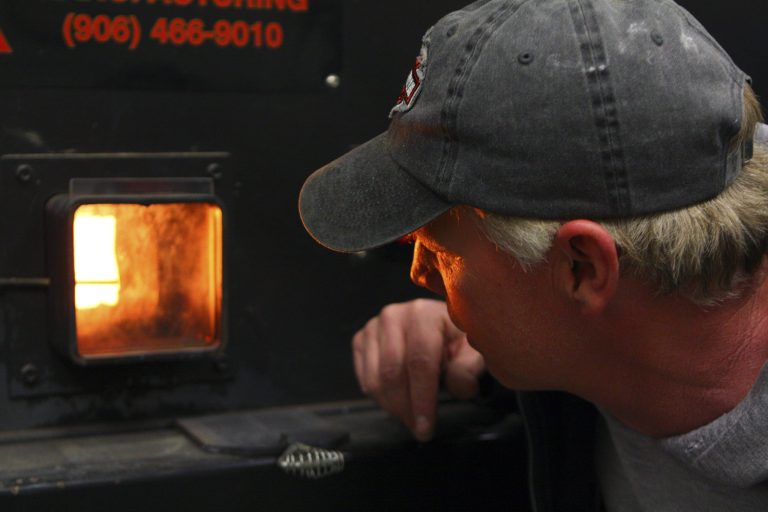 In this April 15, 2014 photo, Jeff Woodbury, assistant school facilities director checks, on a wood heat furnace used by schools in Falmouth, Maine. The furnace was partially funded from a grant of federal stimulus dollars to the Maine Forest Service. The grant program helped 24 facilities slash costs for the heating season ending in 2013 by replacing nearly 900,000 gallons of heating oil with locally produced wood chips and pellets. (AP Photo/Blake Davis)