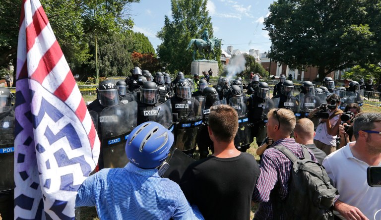 White nationalist demonstrators hold their ground against Virginia State Police as police fire tear gas rounds in Lee Park in Charlottesville, Va. (AP Photo/Steve Helber)