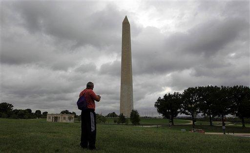 A tourist takes a picture of the recently damaged Washington Monument as clouds from Hurricane Irene moves up the Eastern Seaboard towards Washington, Saturday, Aug. 27, 2011. The monument has been closed to the public it was damaged in the earthquake that shook the capital last Tuesday. (AP Photo/Luis M. Alvarez)