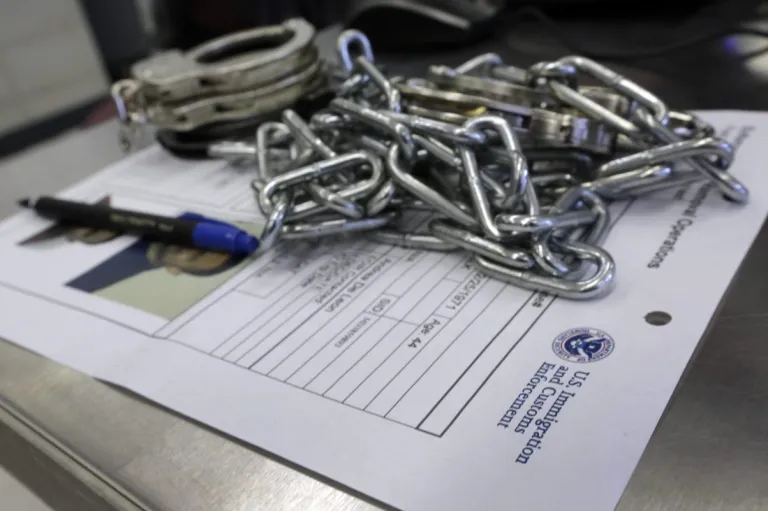 In this March 3, 2015 photo, handcuffs and chains sit on the paperwork of a person arrested by Immigration and Customs Enforcement officers after a series of early-morning arrests in New York. Immigrant and Customs Enforcement say an increasing number of cities and counties across the United States are limiting cooperation with the agency and putting its officers in dangerous situations as they track down foreign-born criminals. (AP Photo/Richard Drew)