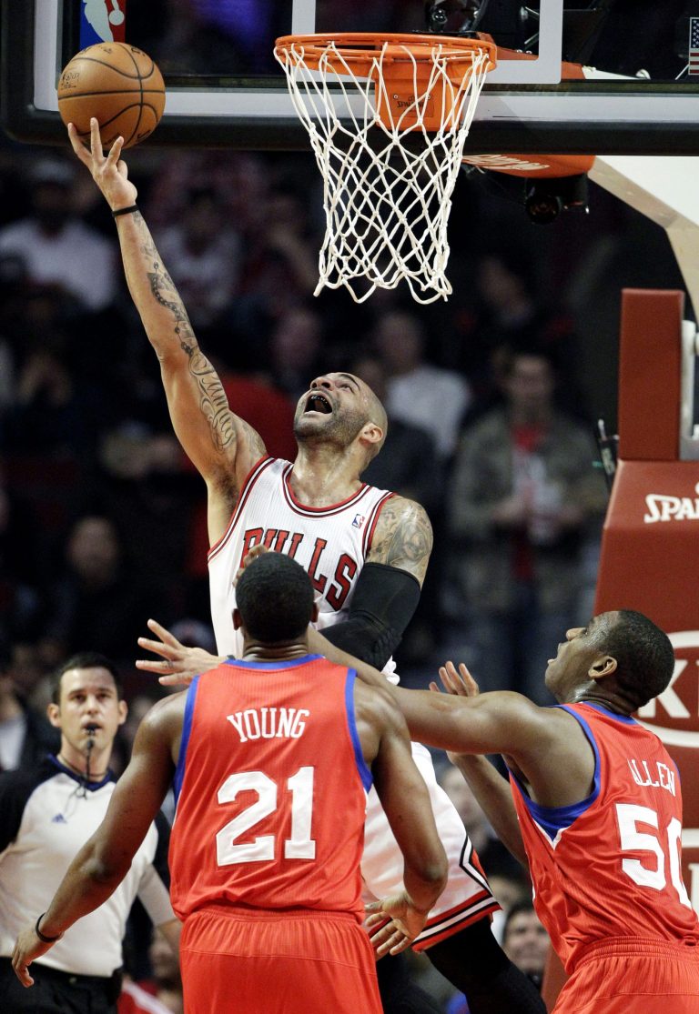   Chicago Bulls forward Carlos Boozer, top, shoots as Philadelphia 76ers forward Thaddeus Young (21) and center Lavoy Allen (50) look on during the first half of an NBA basketball game in Chicago on Saturday, Dec. 1, 2012. (AP Photo/Nam Y. Huh)  