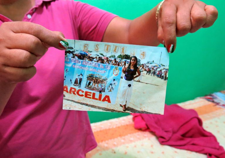 In this Sept. 15, 2014 photo, a woman who did not want to give her name for fear of reprisals, holds up a photograph of her late 15-year-old daughter Erika Gomez Gonzalez, at her home in Arcelia, Mexico. The woman says she witnessed her child's death when army soldiers fired first at an armed group at a grain warehouse on June 30 in the town of San Pedro Limon, Mexico. She said one man died in the initial shootout, when the rest of the gunmen surrendered on the promise they would not be hurt. She recalls that her daughter, who was face down in the ground with a bullet in her leg, was rolled over while she was still alive and shot more than half a dozen times in the chest. The mother said she arrived to the warehouse the day before the shooting, in an attempt to take her daughter home, but gang members wouldn't let her. (AP Photo/Eduardo Castillo)