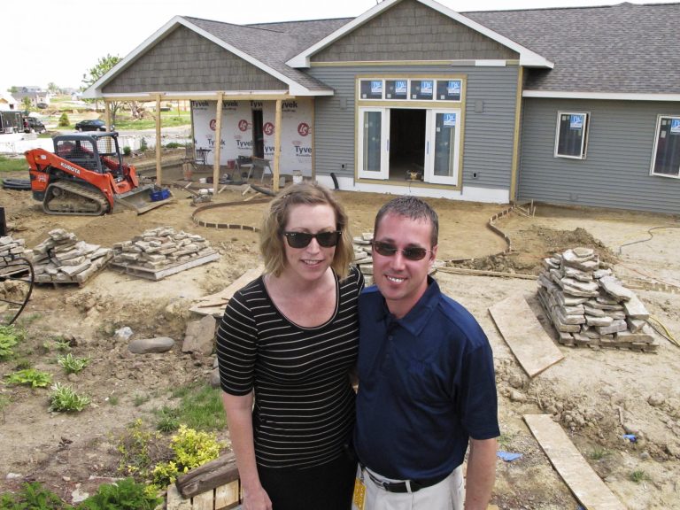 In this May 28, 2014 photo, Jamie and Daniel Cobb pose in the backyard of the their home, now being rebuilt, in Washington, Ill. The Cobbs had lived in their house less than a year when it was destroyed by a tornado in November 2013. The couple expect to be able to move back in within a few months. (AP Photo/David Mercer)