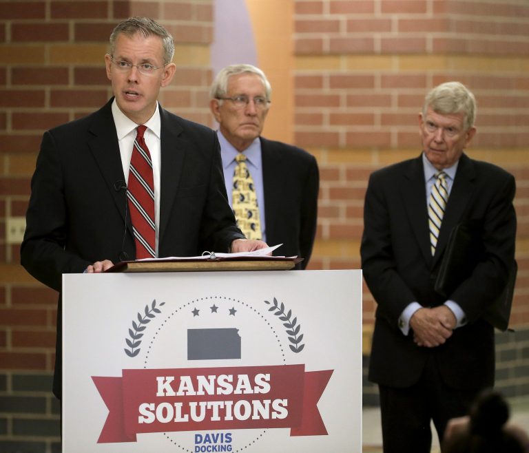 The presumed Democratic nominee for Kansas governor Paul Davis, left, stands with former Lt. Govs. Gary Sherrer, center, and John Moore as he talks to the media during a news conference Monday, June 30, 2014, in Piper, Kan. Davis outlined a proposal to postpone future Kansas tax cuts if he were elected. (AP Photo/Charlie Riedel)