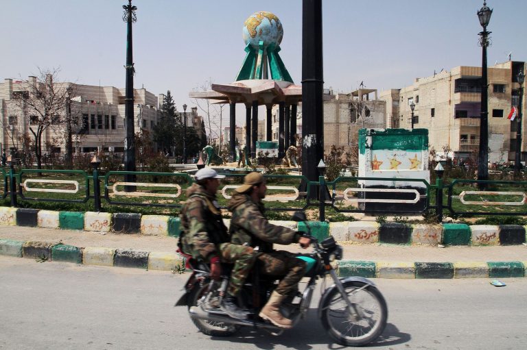 Syrian government forces ride a motorcycle around the main square after being deployed in Yabroud town, Syria, Sunday, March 16, 2014. Syrian troops backed by Hezbollah fighters seized a key rebel supply town on the Lebanese border on Sunday, driving them from the area and scoring a major blow against them in the three-year-old-conflict. The fall of Yabroud immediately emboldened government forces to attack nearby rebel-held towns, pressing forward in what has been nearly a yearlong advance against rebels fighting to overthrow President Bashar Assad. The Syrian revolutionary flag is seen painted at right. (AP Photo)