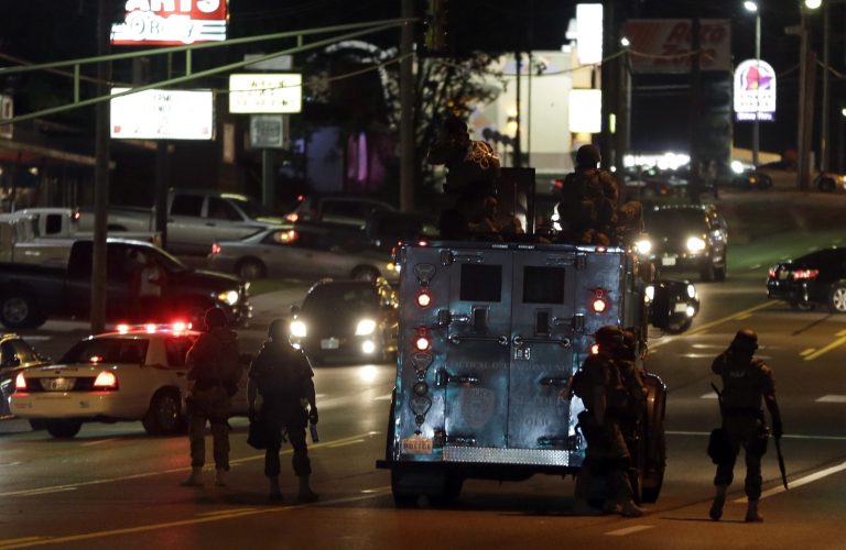 Police attempt to secure a street after a clash with protesters Wednesday, Aug. 13, 2014, in Ferguson, Mo.  Protests in the St. Louis suburb rocked by racial unrest since a white police officer shot an unarmed black teenager to death turned violent Wednesday night, with people lobbing molotov cocktails at police who responded with smoke bombs and tear gas to disperse the crowd.  (AP Photo/Jeff Roberson)