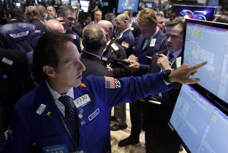 FILE - In this April 30, 2014 file photo, Specialist Glenn Carell, foreground, works with traders at the post that handles Under Armour on the floor of the New York Stock Exchange. Stocks edged lower on Thursday, May 1, 2014, as investors assessed the latest round of company earnings, a survey on manufacturing and news on hiring. Satellite TV company Dish gained on reports that AT&T had approached the company about a merger. (AP Photo, File)