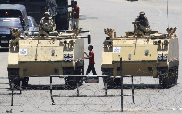   FILE - This Aug. 23, 2013 file photo shows an Egyptian walking between armored vehicles blocking Tahrir Square in Cairo, Egypt. U.S. officials say President Barack Obamaâs top national security aides have recommended that the U.S. suspend hundreds of millions of dollars in military and economic assistance to Egypt in response to the Egyptian militaryâs ouster of the countryâs first democratically elected leader. (AP Photo/Amr Nabil, File)  