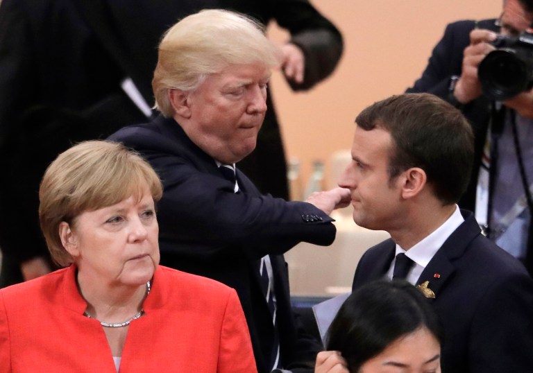 German Chancellor Angela Merkel, front, looks on as U.S. President Donald Trump, center, pads the shoulder of France's President Emmanuel Macron prior to the first working session on the first day of the G-20 summit in Hamburg, northern Germany, Friday, July 7, 2017. The leaders of the group of 20 meet July 7 and 8. (AP Photo/Markus Schreiber)