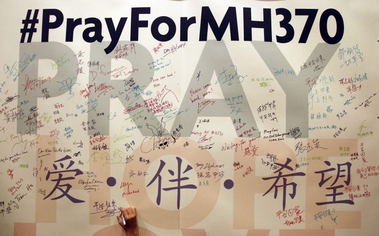 FILE - In this April 6, 2014 file photo, a man writes messages for passengers aboard the missing Malaysia Airlines Flight MH370 before a mass prayer for them, in Kuala Lumpur, Malaysia.  The Malaysian government on Tuesday, May 27, 2014, released 47 pages of raw satellite data used to conclude that the missing Malaysia Airlines jet crashed into the southern Indian Ocean.  (AP Photo/Lai Seng Sin, File)