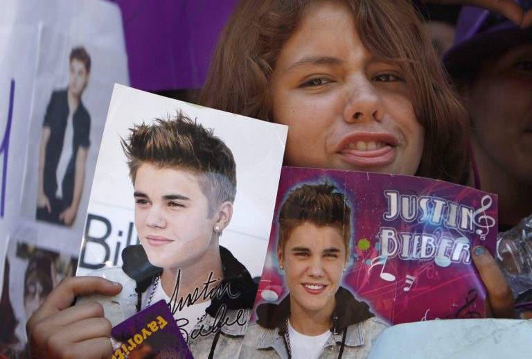   A fan holds images of pop starJustin Bieber in Mexico City's main historic plaza, the Zocalo, Sunday, June 10, 2012. The Beliebers have arrived in the chaotic streets of Mexico City, adolescents in purple and white and braving two nights on roach-infested sidewalks for a chance to be closest to the stage when teenage superstar Justin Bieber puts on a free concert Monday evening on the capital's vast central plaza. (AP Photo/Marco Ugarte)  