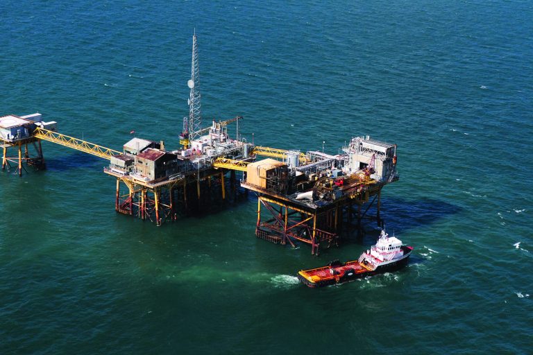 In this aerial photograph, a supply vessel moves near an oil rig damaged by an explosion and fire, Friday, Nov. 16, 2012, in the Gulf of Mexico about 25 miles southeast of Grand Isle, La. Four people were transported to a hospital with critical burns and two were missing. (AP Photo/Gerald Herbert)