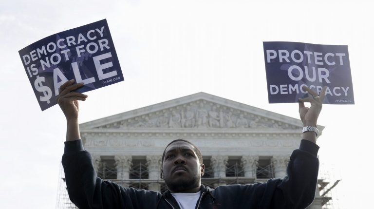 FILE - This Oct. 8, 2013 file photo shows Cornell Woolridge of Windsor Mill, Md., takes part in a demonstration outside the Supreme Court in Washington as the court heard arguments on campaign finance. The Supreme Court struck down limits Wednesday in federal law on the overall campaign contributions the biggest individual donors may make to candidates, political parties and political action committees. The justices said in a 5-4 vote that Americans have a right to give the legal maximum to candidates for Congress and president, as well as to parties and PACs, without worrying that they will violate the law when they bump up against a limit on all contributions, set at $123,200 for 2013 and 2014. That includes a separate $48,600 cap on contributions to candidates.   (AP Photo/Susan Walsh, File)