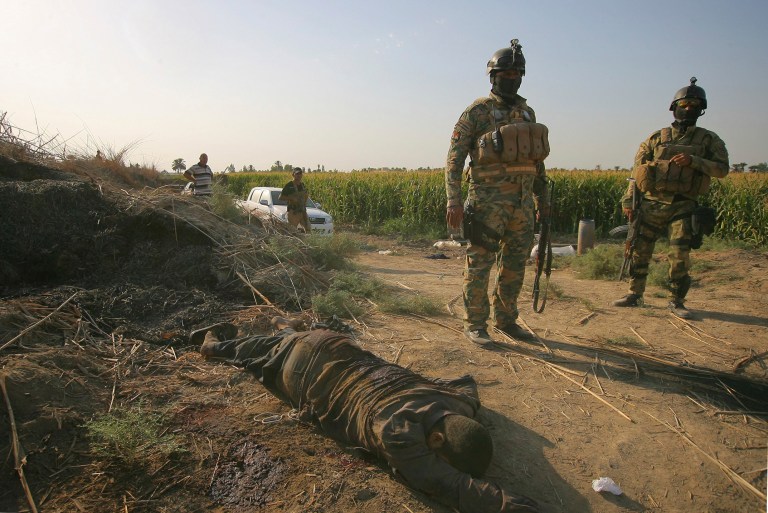 Iraqi security forces inspect the lifeless bodies of a militant from the Islamic State group after clashes, near the town of Jbala, about 35 miles (56 kilometers) south of Baghdad, Iraq, Saturday, Oct. 4, 2014. (AP Photo)