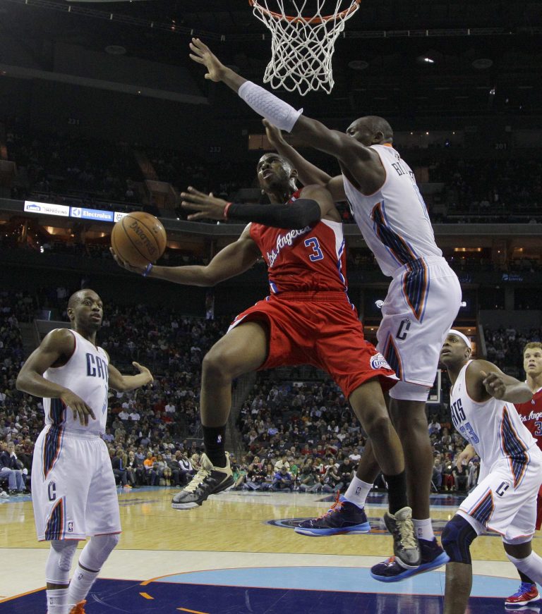   Los Angeles Clippers' Chris Paul, center, shoots as Charlotte Bobcats' Bismack Biyombo, right, and Kemba Walker, left, defend during the first half of an NBA basketball game in Charlotte, N.C., Wednesday, Dec. 12, 2012. (AP Photo/Chuck Burton)  