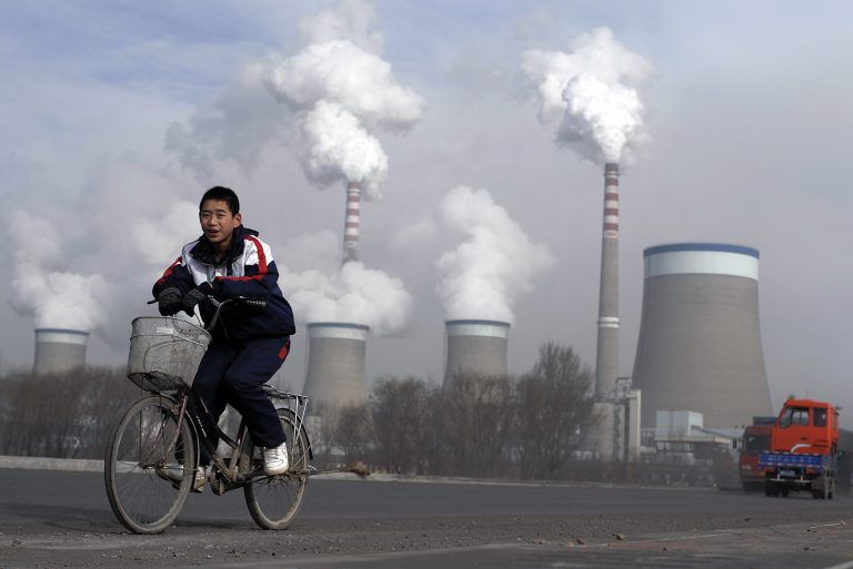 FILE - In this Dec. 3, 2009 file photo, a Chinese boy cycles past a cooling towers of a coal-fired power plant in Dadong, Shanxi province, China. President Barack Obama's proposal to curb U.S. greenhouse gas emissions might improve the chances of completing a global climate treaty but is unlikely to defuse demands by China, India and others for Americans to do more. China, the biggest emitter, has promised to curb its output but with its economy slowing, and communist leaders under pressure to generate jobs, has resisted binding limits. (AP Photo/Andy Wong, File)