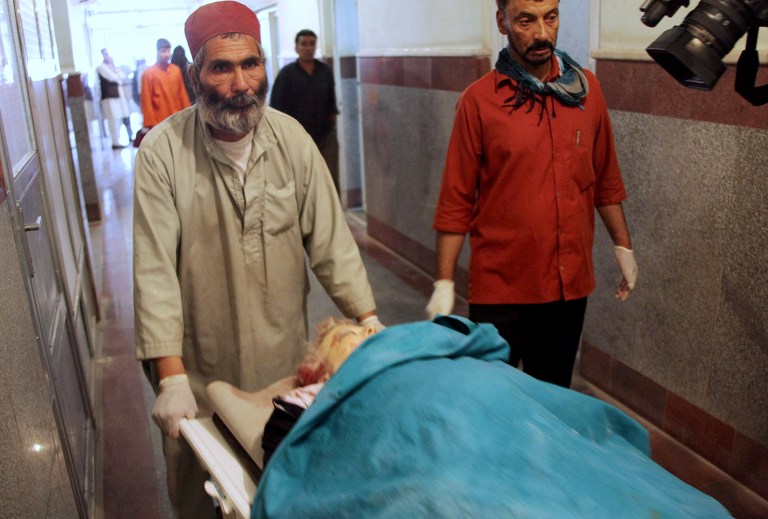 Afghan medical workers move the dead body of a foreign female aid worker who was employed by the International Assistance Mission, in Herat, west of Kabul, Afghanistan, Thursday, July 24, 2014. Officials said two Finnish women were riding in a taxi when they were shot dead by two men on a motorcycle. (AP Photo/Hoshang Hashimi)