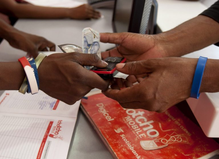   In this June 4, 2012 photo, a man takes his money, along with his cell phone, at Digicel's 