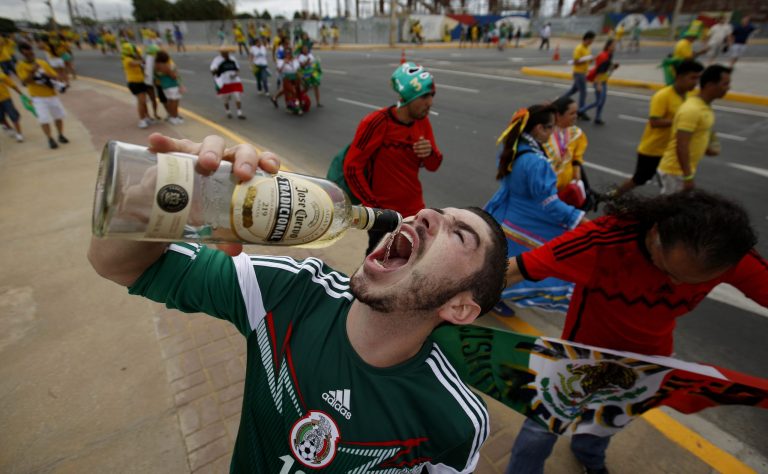 A Mexican fans drinks tequila outside of the Arena Castelao stadium before the group A World Cup soccer match between Brazil and Mexico in Fortaleza, Brazil, Tuesday, June 17, 2014. Many of the soccer fans traveling from the U.S. to Brazil, are part of the last great wave of Mexican migration to the United States, which spanned the 1990s to the mid-2000s. Others are second-generation Mexicans who grew up rooting for the Mexican team at a time when Team USA was still unknown. (AP Photo/Eduardo Verdugo)