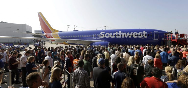 Southwest Airlines employees crowd around a newly unveiled plane paint color scheme during an event at Love Field Monday, Sept. 8, 2014, in Dallas. The change comes in a year during which 43-year-old Southwest has begun international flights, expanded in New York and Washington, and is freed from longtime government limits on its Dallas schedule. (AP Photo/LM Otero)