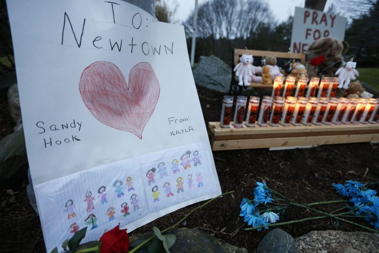  A child's message rests with a memorial for shooting victims, Sunday, Dec. 16, 2012, in Newtown, Conn. A gunman walked into Sandy Hook Elementary School in Newtown on Friday and opened fire, killing 26 people, including 20 children. (AP Photo/Jason DeCrow)  