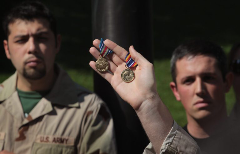 Illinois Army National Guard veteran Aaron Hughes holds up his Global War on Terrorism Expeditionary Medal and War on Terrorism Service Medal during a protest with Iraq Veterans Against the War in the Loop May 17, 2012 in Chicago. (Photo by Scott Olson/Getty images)