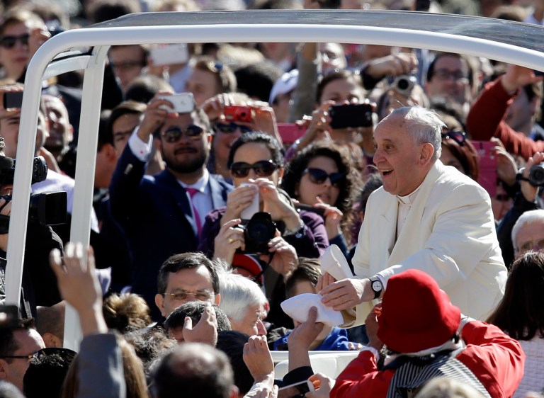 Pope Francis exchanges a skull cap with a participant in the audience  as he tours with his pope mobile St. Peter's Square at the Vatican , Wednesday, April 16, 2014.  (AP Photo/Gregorio Borgia)