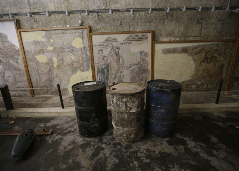 In this photo taken Tuesday, Feb. 26, 2013, fuel barrels are stored in front of Roman and Byzantine mosaics inside the 17th-century caravanserai, which presently serves as a headquarters for the Free Syrian Army, in Maaret al-Numan, Idlib province, Syria. Across northern Syria, rebels, soldiers and civilians are making use of the country's wealth of ancient and medieval remains for protection. The structures are built of thick stone that has already withstood the ravages of centuries. They are often located in strategic spots overlooking towns and roads. (AP Photo/Hussein Malla)