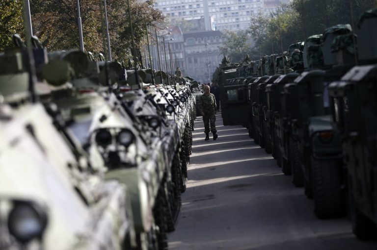A Serbian army soldier walks alongside armored personal carriers parked in Usce park, two days before an upcoming military parade, in Belgrade, Serbia, Tuesday, Oct. 14, 2014. Serbia is preparing to stage a hero's welcome for Russian President Vladimir Putin with the country's first military parade in 30 years - the red carpet reception considered by some in the West as highly inappropriate for the leader accused of warmongering in Ukraine. (AP Photo/Darko Vojinovic)
