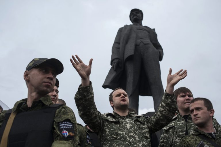 Pavel Gubarev, center, self-proclaimed people's governor, surrounded by pro-Russian fighters, speaks before taking the oath of allegiance to the self-proclaimed Donetsk People's Republic, on Lenin square in Donetsk, eastern Ukraine, Saturday, June 21, 2014. Dozens of pro-Russian armed militiamen gathered on Lenin square in Donetsk on Saturday to take the oath of allegiance to the so-called Donetsk People's Republic after Ukrainian President Petro Poroshenko ordered his forces to cease fire Friday and halt military operations for a week. In the background is a monument of Vladimir Lenin. (AP Photo/Evgeniy Maloletka)