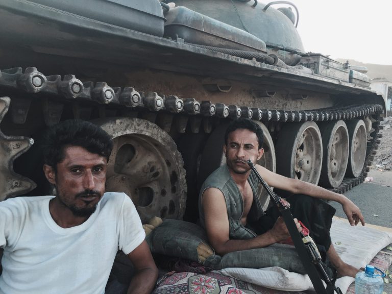 Members of a militia group loyal to Yemen's President Abed Rabbo Mansour Hadi, known as the Popular Committees, chew qat, Yemen's favorite drug, as they sit next to their tank, guarding a major intersection in Aden, Yemen, Saturday, March 21, 2015. (AP Photo/Hamza Hendawi)