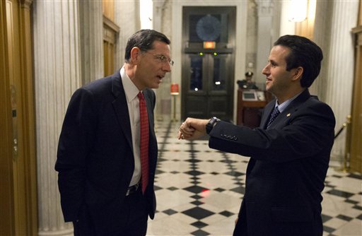 Sen. John Barrasso, left, R-Wyo., talks with Sen. Brian Schatz, D-Hawaii, who holds up his watch, near the Senate chambers after a vote on the fiscal cliff, on Capitol Hill Tuesday, Jan. 1, 2013 in Washington. The Senate passed legislation early New Year's Day to neutralize a fiscal cliff combination of across-the-board tax increases and spending cuts that kicked in at midnight. (AP Photo/Alex Brandon)
