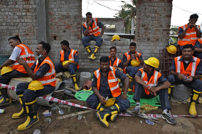 Indian rescuers, take a break as they search for workers believed buried in the rubble of a building that collapsed late Saturday during monsoon rains on the outskirts of Chennai, India, Monday, June 30, 2014. Rescuers have pulled at least 41 people from the wreckage, even as seasonal monsoon rains impeded the search. Police said 30 other people are likely still trapped. (AP Photo/Arun Sankar K)