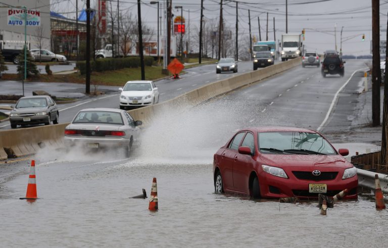   A vehicle stands abandoned facing in the wrong direction as traffic flows around floodwaters on Route 35 in Keyport, N.J., where an overnight storm caused coastal flooding, Thursday, Dec. 27, 2012. (AP Photo/Julio Cortez)  
