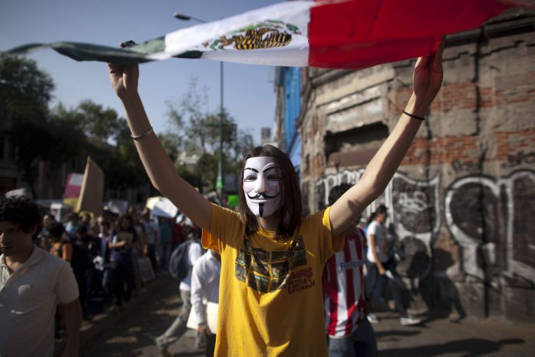   FILE - In this May 28, 2012 file photo, a demonstrator holds up Mexico's national flag during a protest against a possible return of the old ruling Institutional Revolutionary Party (PRI) in Mexico City. Students challenged presidential candidates to debates, urged others their age to pay attention to the campaign, and sought to fight off the return of the Institutional Revolutionary Party, which held power for 71 years until its ouster in 2000. Mexico will hold presidential elections on July 1. (AP Photo/Alexandre Meneghini, file)  