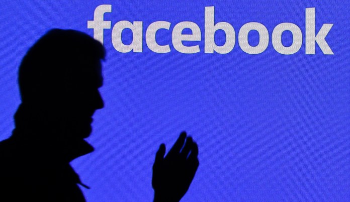 A man passes a Facebook screen at the Gamescom in Cologne, Germany.