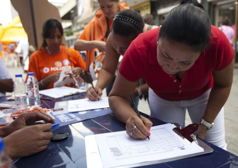 Women sign a petition to force a constitutional assembly that would seek to remove President Nicolas Maduro from office, in Caracas, Venezuela, Saturday, Sept. 27, 2014. Hardliner opponents of Maduro began collecting signatures Saturday, to force a constitutional assembly and remove the leader before presidential elections in 2019. The Popular Will party led by jailed activist Leopoldo Lopez is launching the petition campaign. (AP Photo/Ariana Cubillos)